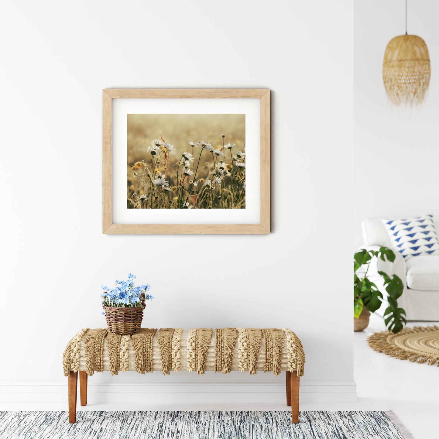 photograph of daisies in a light frame on a wall above a bench